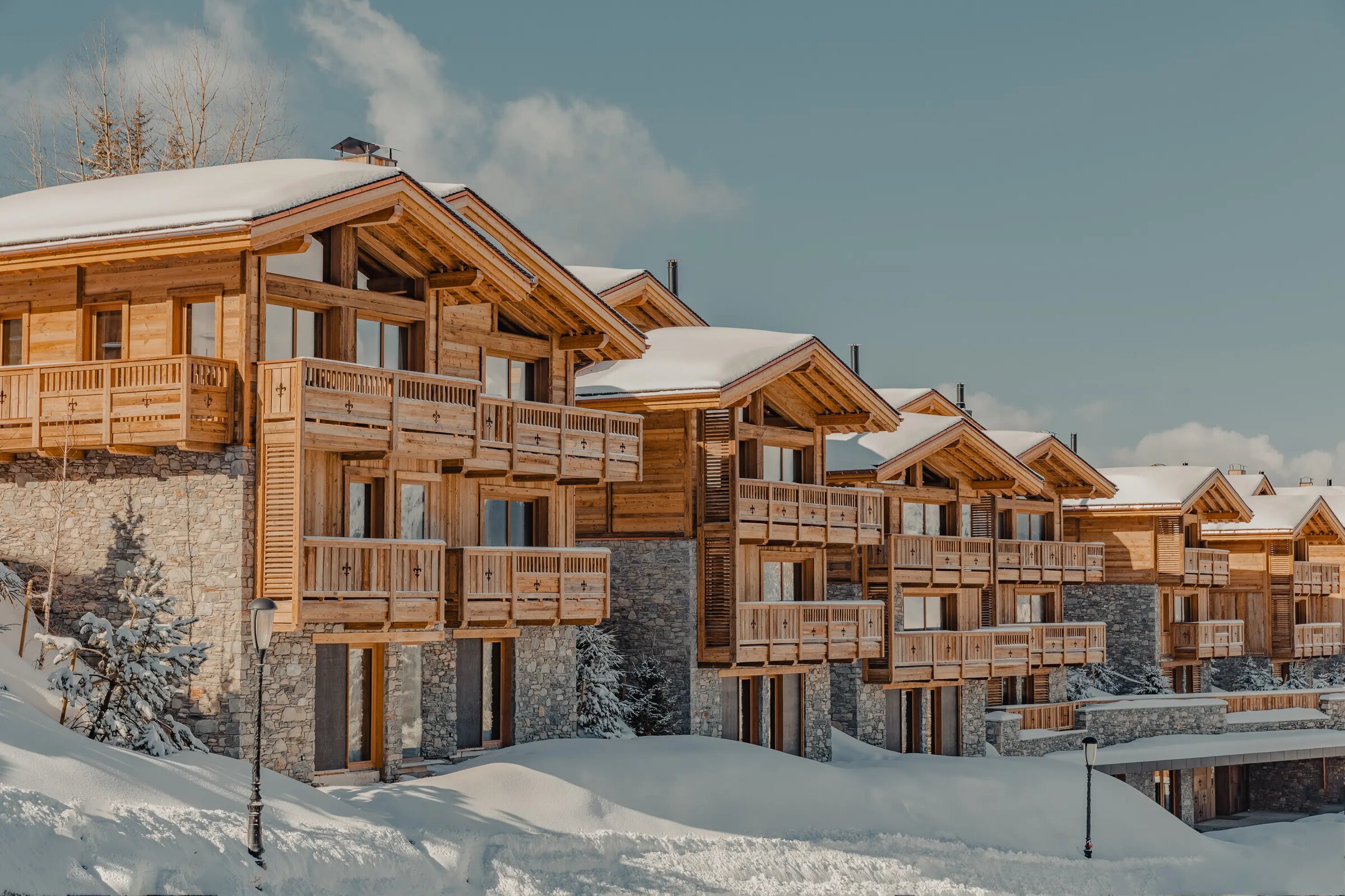 Vue d'ensemble du Hameau Courchevel, alignement de chalets en bois noble sous la neige des Trois Vallées
