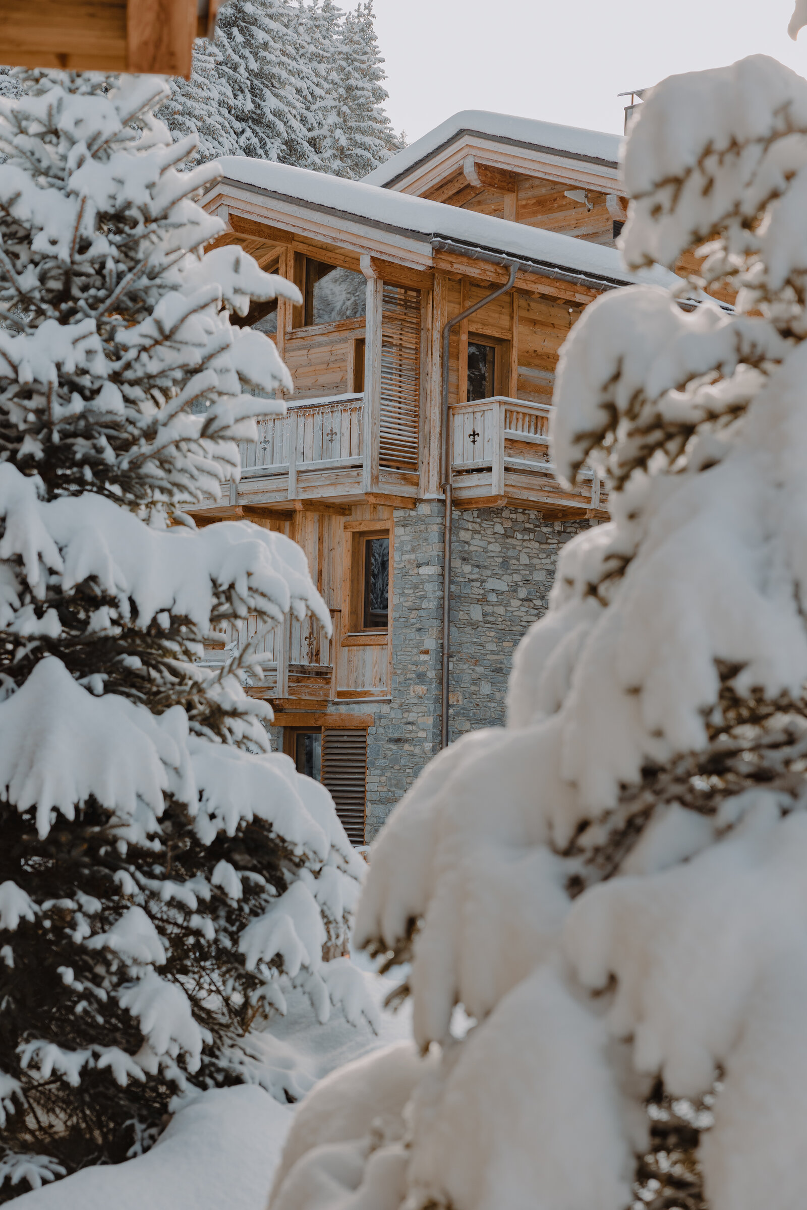 Chalet de luxe Courchevel à travers les sapins enneigés, atmosphère feutrée du hameau