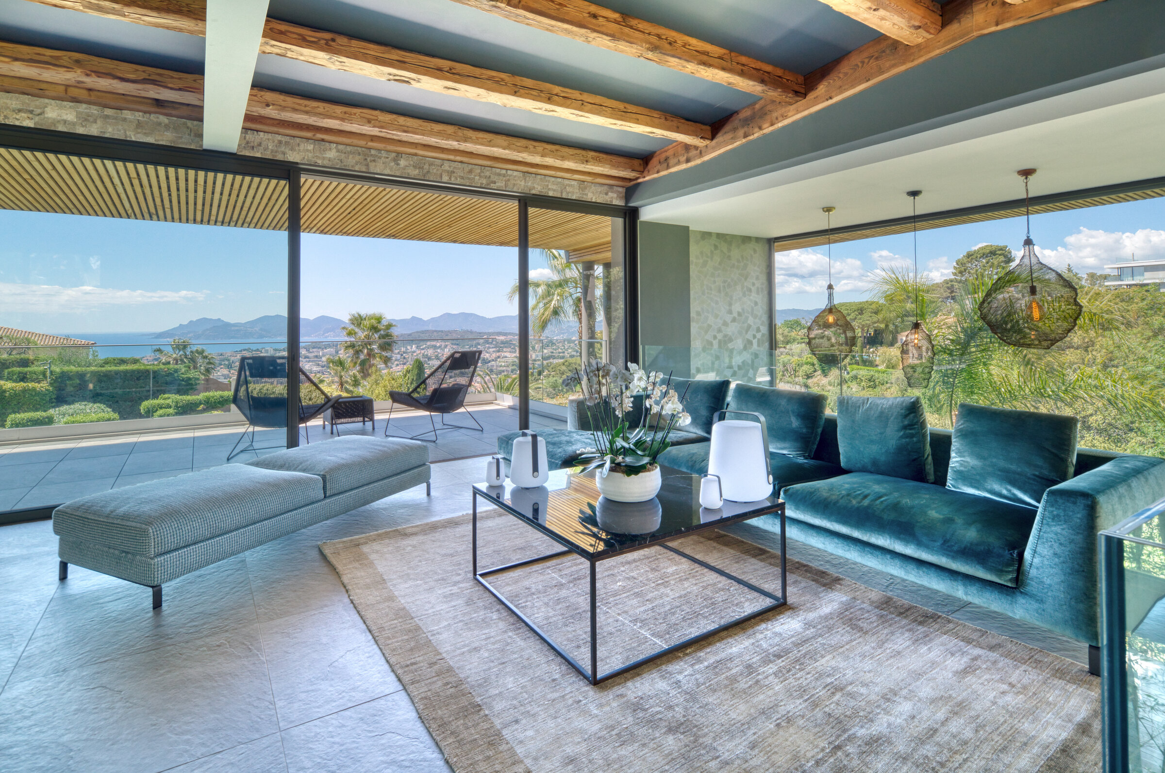 Salon principal avec canapé velours bleu, poutres anciennes et vue traversante sur la baie de Cannes, Villa Bali