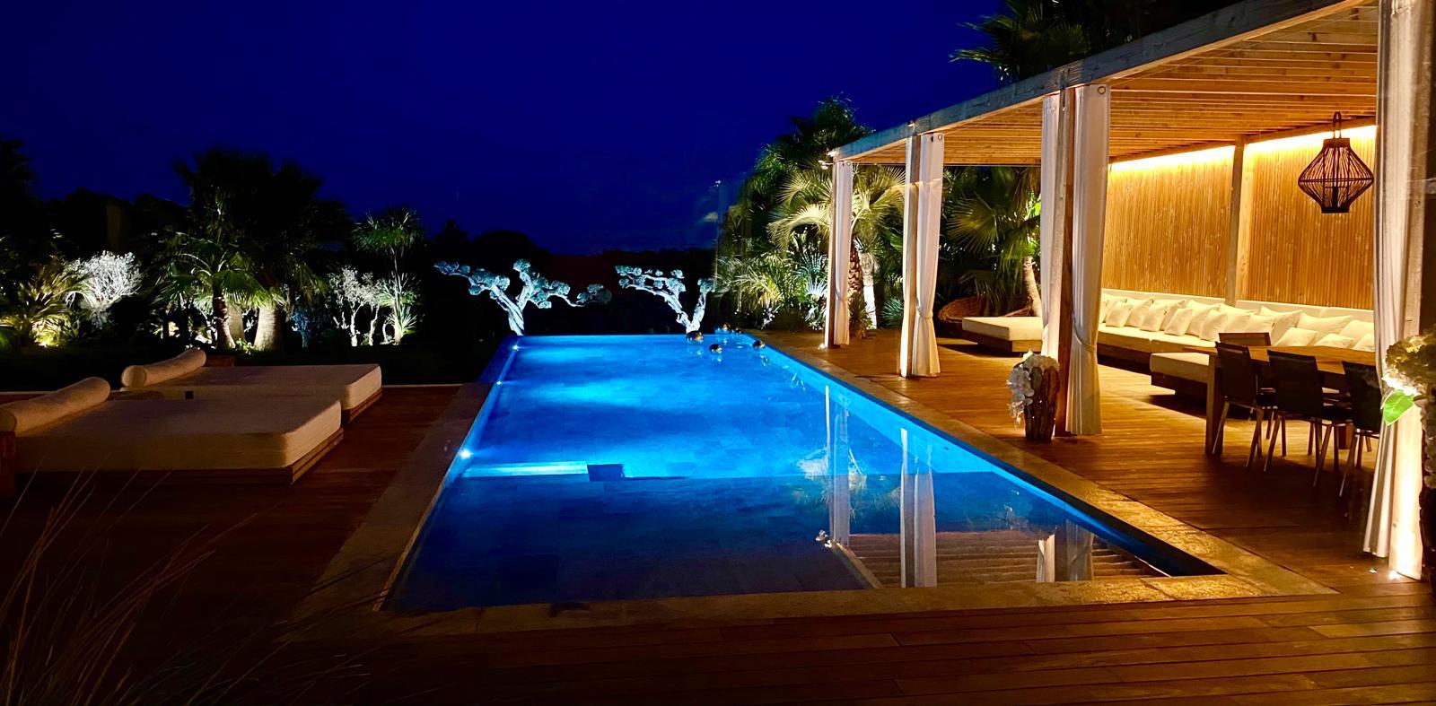 Piscine à débordement éclairée la nuit avec oliviers illuminés, Villa Mougins