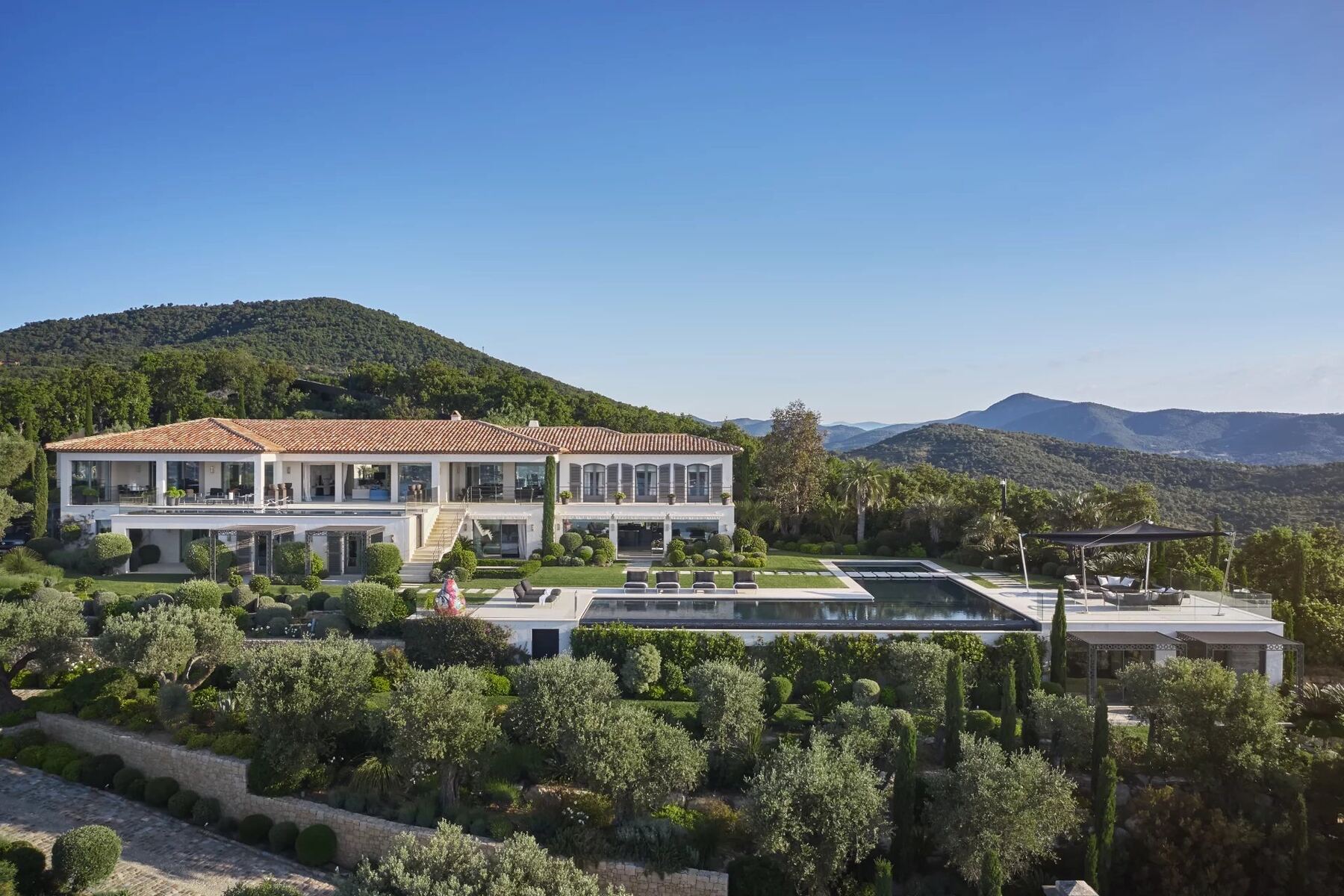 Vue large de la villa de luxe Saint-Tropez avec piscine à débordement et collines des Maures